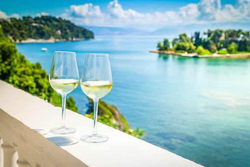 Two glasses of white wine with Corfu seascape in background