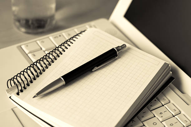 istock Black pen sitting on a notepad which is laying on a laptop 140268472