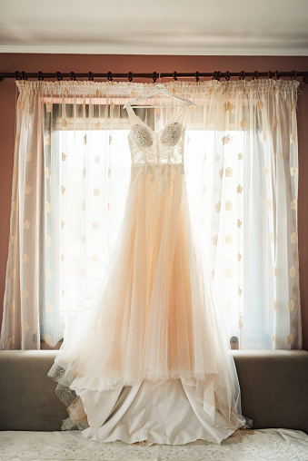 A wedding dress hanging on a window