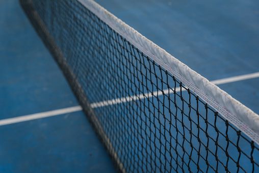 Close up of nylon tennis net across a blue court. in Kingston, Ontario, Canada