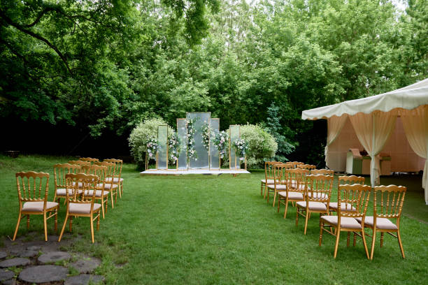 Place for wedding ceremony in garden outdoors, copy space. Wedding arch decorated with flowers and chairs on each side of archway. Wedding setting stock photo