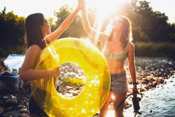 Two young women cool off in the river, spray themselves and enjoy the beautiful weather