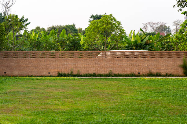 ceglana ściana, bariera ogrodzeniowa jest zaprojektowana z otworem na szczycie ściany w stylu azjatyckim z trawą ogrodową na pierwszym planie - plant orange wall architecture zdjęcia i obrazy z banku zdjęć