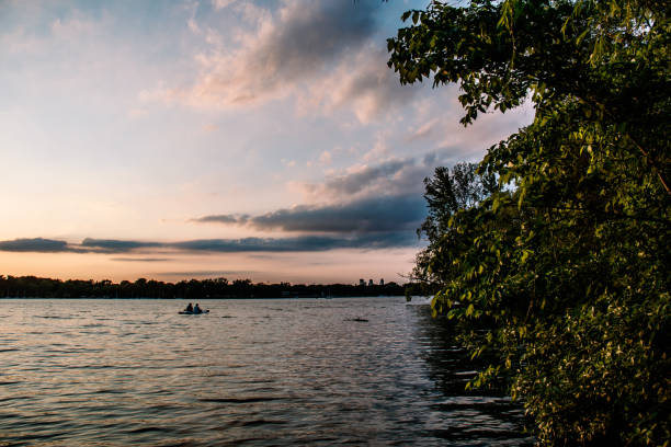 Horizontal color photograph of a paddle boat on Lake Nokomis in Minneapolis, MN at sunset.