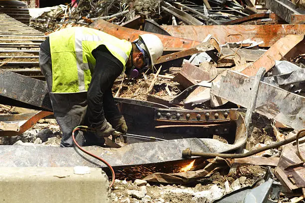 Photo of Construction Worker Cutting Scrap Metal Girder Building Demolition Site