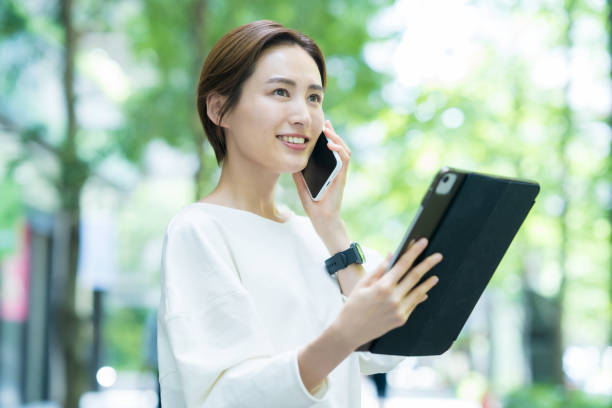 タブレットを操作しながらスマホで話す女性 - businesswoman business mobile phone business person ストックフォトと画像