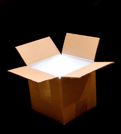 A cardboard box with light bursting from within.
