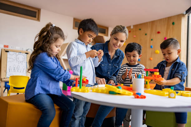 istock Teacher playing with toy blocks with a group of elementary students 1402700261