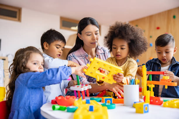 istock Happy teacher playing in the classroom with a group of young students 1402700263