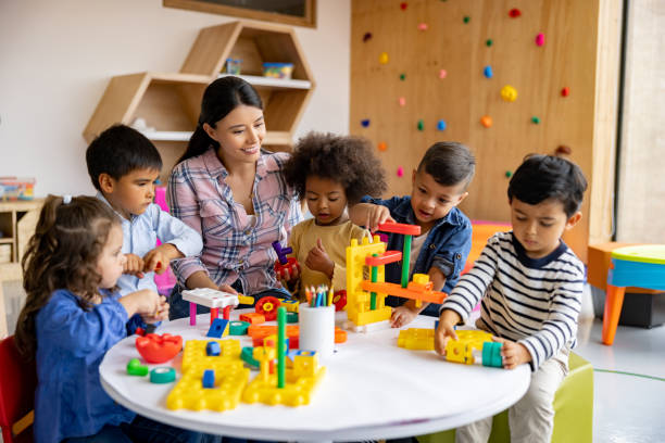 insegnante con un gruppo di studenti delle elementari che giocano con i blocchi giocattolo - child preschool toy playing foto e immagini stock