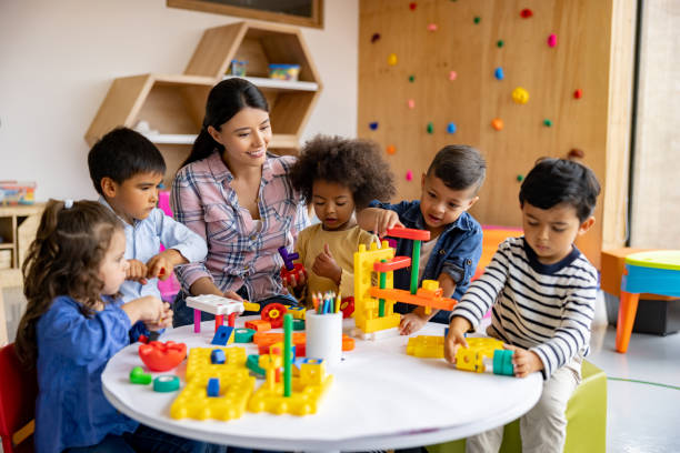 Teacher with a group of elementary students playing with toy blocks stock photo