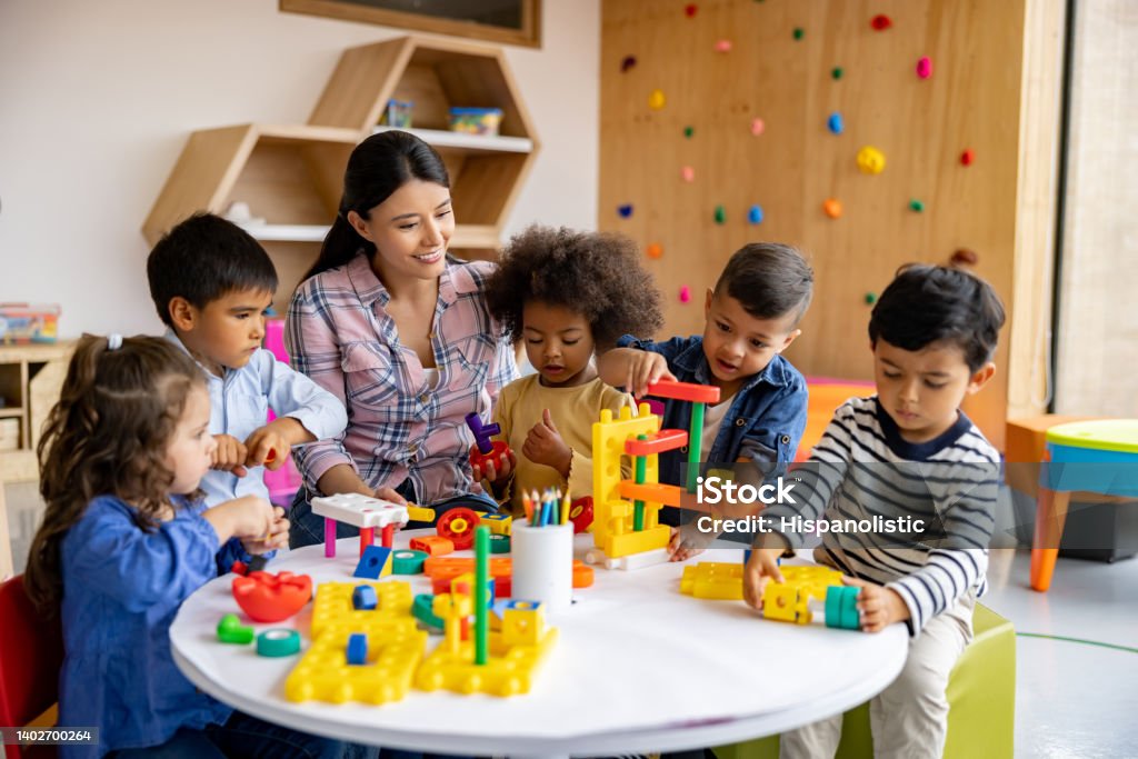 Teacher with a group of elementary students playing with toy blocks - Royaltyfri Förskola Bildbanksbilder Teacher with a group of elementary students playing with toy blocks - Royaltyfri Förskola Bildbanksbilder