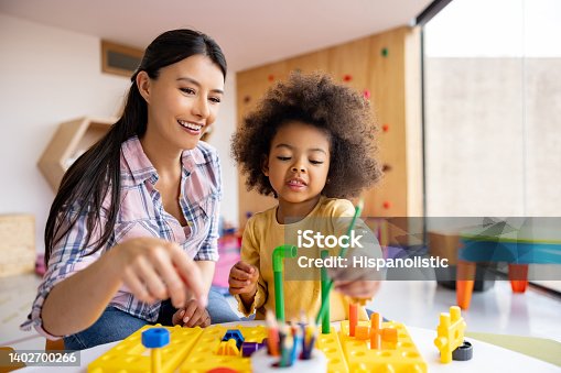 istock Happy teacher playing with a girl in the classroom 1402700266