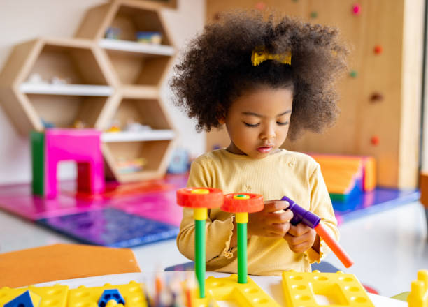 ragazza afroamericana che gioca con i mattoni a scuola - child preschool toy playing foto e immagini stock