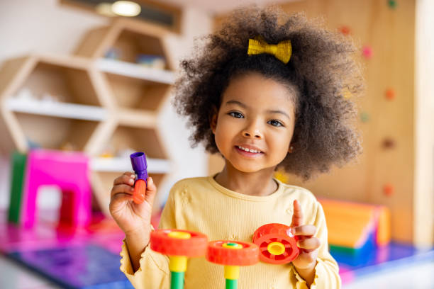 Beautiful girl playing with building blocks at the school Portrait of a beautiful African American girl playing with building blocks at the school and looking at the camera smiling preschool photos stock pictures, royalty-free photos & images