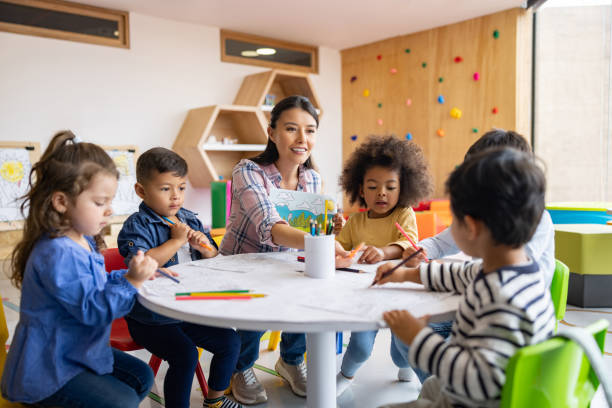 grupo de niños coloreando en clase de arte con la supervisión de su profesor - preschool fotografías e imágenes de stock