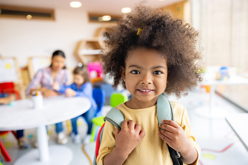 Portrait of a happy African American girl arriving to elementary school with her backpack and looking at the camera smiling