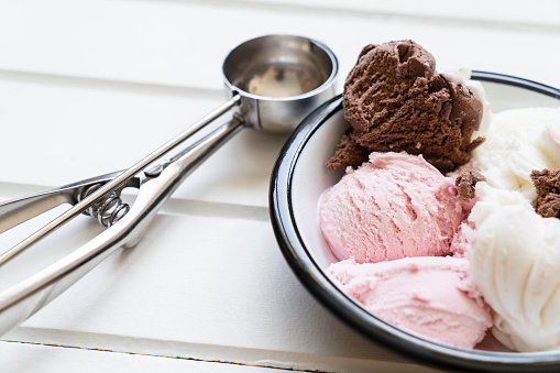 Chocolate, strawberry and vanilla ice cream in a bowl on wooden table