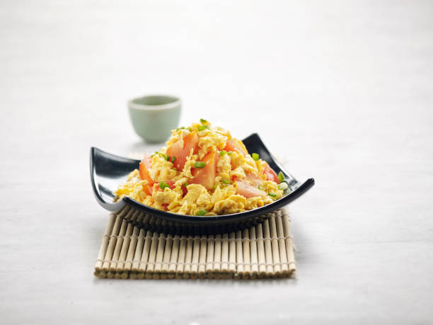 istock Fried Eggs with Tomato in a dish with sauce isolated on wooden mat side view on grey background a morning meal 1402703501
