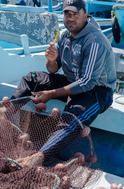 fischer nähen fischernetze im ägyptischen hafen - fishing boat egypt men middle eastern ethnicity stock-fotos und bilder