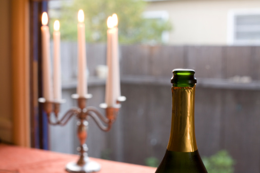 champagne bottle on table with candles in background