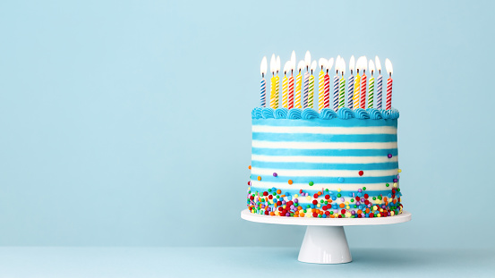 Striped buttercream birthday cake with colorful birthday candles and sprinkles