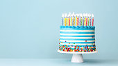 istock Striped buttercream birthday cake with colorful birthday candles and sprinkles 1402705959