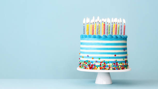 Striped buttercream birthday cake with colorful birthday candles and sprinkles Striped buttercream birthday cake with colorful birthday candles and sprinkles on a blue background birthday stock pictures, royalty-free photos & images