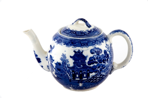 Small blue willow pattern tea pot with spout facing left and handle facing right