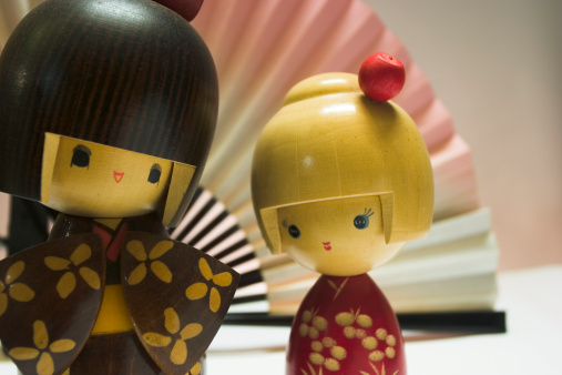 Two Japanese Dolls with a paper fan in the background