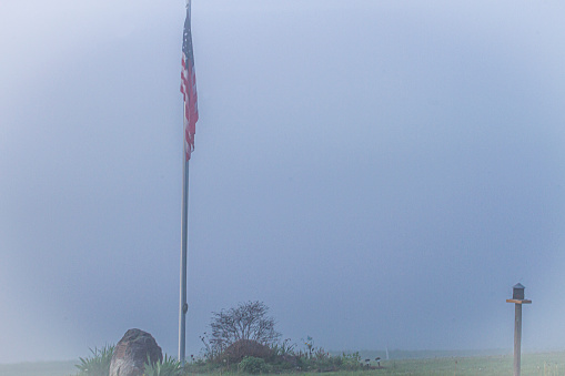 American flag drooping on a foggy morning. Also includes Rock, Bush and Bird Feeder. Lots of Copy space