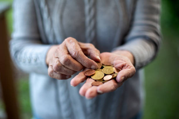 istock older womans hand holding coins and counting 1402710804