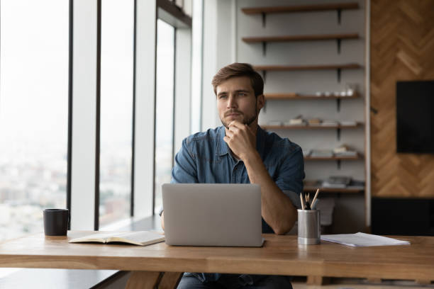 istock Pensive male employee work on laptop thinking 1402711541