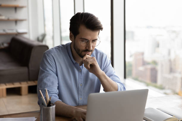 istock Pensive young Caucasian male employee work on computer 1402711551