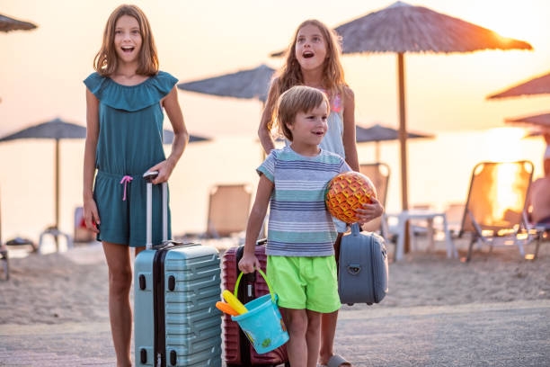 two girls and a boy with suitcases arrived at the sea and they are happy two beautiful girls and a boy with suitcases arrived at the sea and they are happy family beach vacations travel stock pictures, royalty-free photos & images