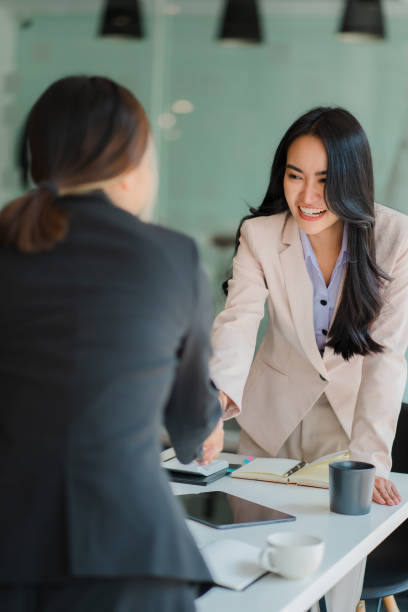 young asian businesswoman and interviewer shaking hands in modern office business meeting, greetings, agreements, ideas after negotiating with her partner. teamwork and success concept - gesturing interview business sitting imagens e fotografias de stock