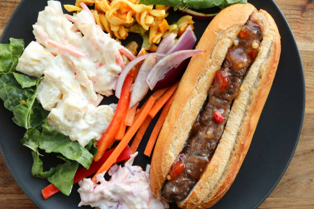Boerewors roll with relish A boerewors roll with relish and salads including coleslaw, potato salad and curry pasta salad. Braai sausage on a crusty roll south african braai stock pictures, royalty-free photos & images