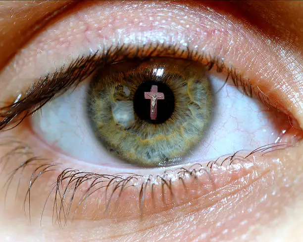Macro of human eye with the reflection of Jesus on the pupil.