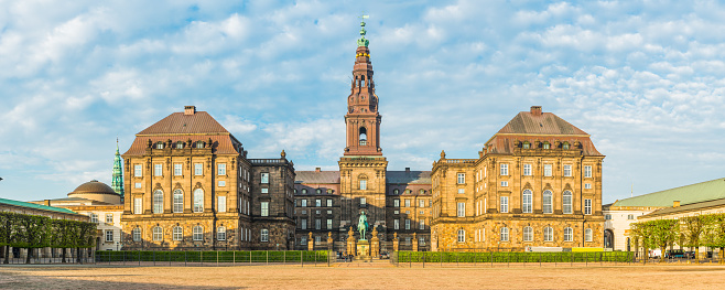 The Riding Ground Complex and fountain in the central courtyard of Christiansborg, home of the Folketing - Danish parliament - the Prime Minister's Office and Danish Supreme Court under blue spring skies in the heart of Copenhagen, Denmark.