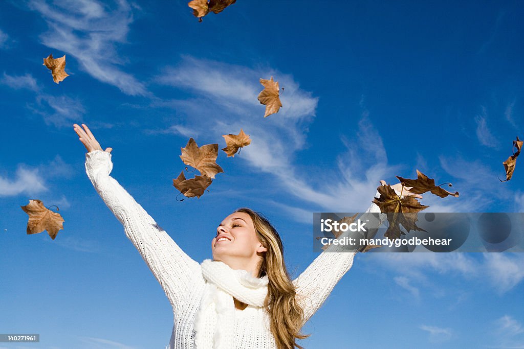 Young woman in white sweater standing under falling leaves girl surrounded by falling autumn leaves Adolescence Stock Photo