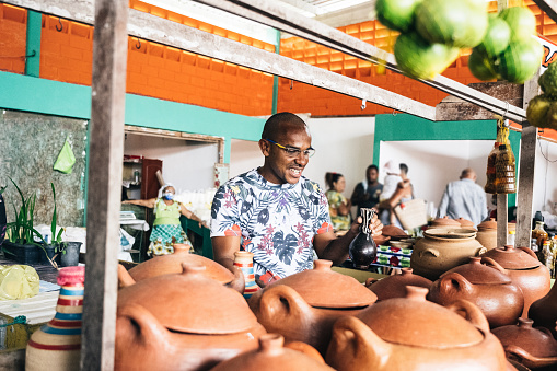 portrait of smiling young market vendor behind his pottery stall at public market in Bahia, Brazil