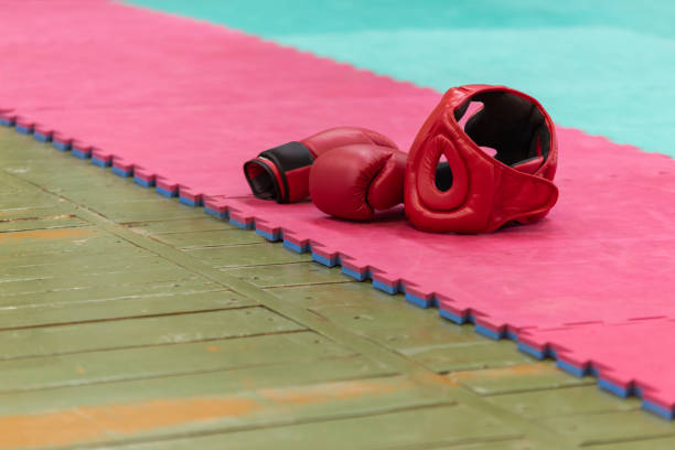 Protective helmet and gloves on the edge of the tatami. Combat sports background in vintage style with film noise effect.