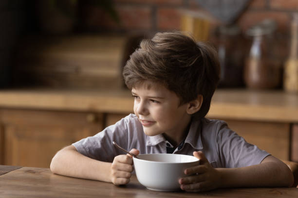 istock Dreamy smiling little child boy eating fast breakfast. 1402723340