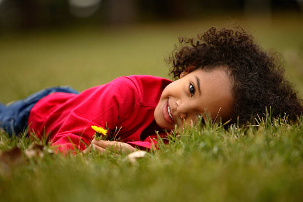 Adorable African American girl laying on grass smiling stock photo