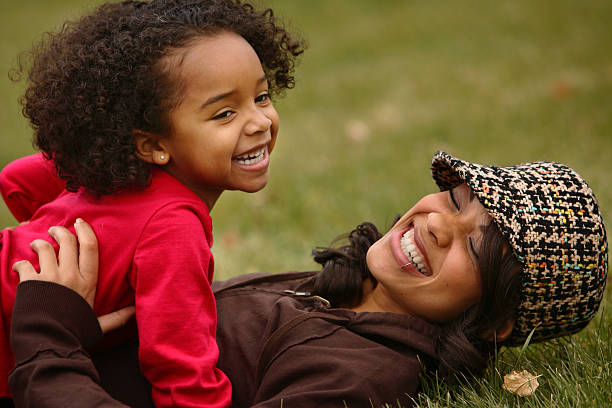 Mother and daughter laugh as they play outdoors stock photo