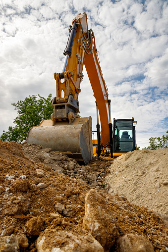 A stopping yellow excavator for rest, at a construction site. Vertical view