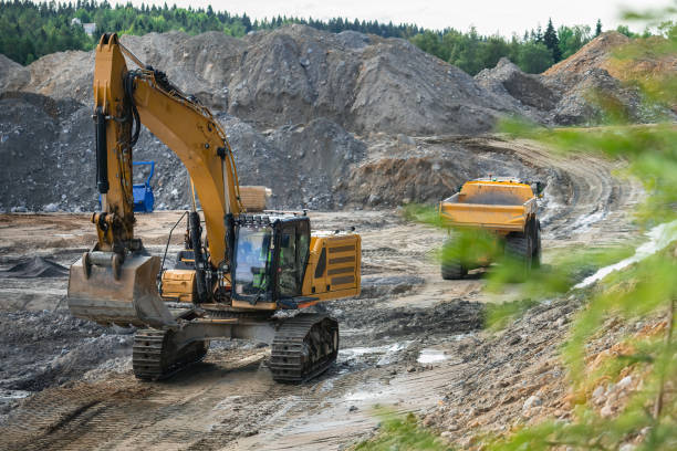 istock Big dump truck waits for loading by excavator - ground preparing for concrete foundations on the site of a new building 1402725855