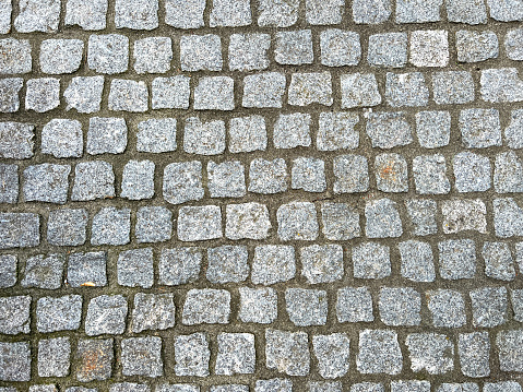 Standard view of granite sidewalk with irregular pairing, characteristic texture with moss in the joints...