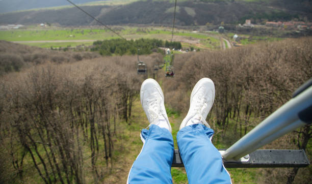 Man sitting in ropeway. Male sneakers