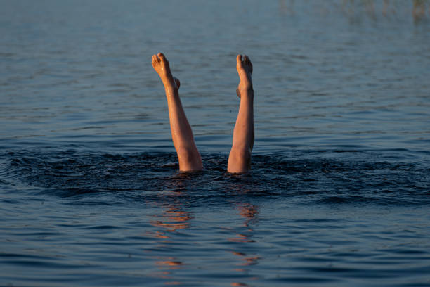 istock A person standing upside down in a lake. Legs visible over water. 1402726230